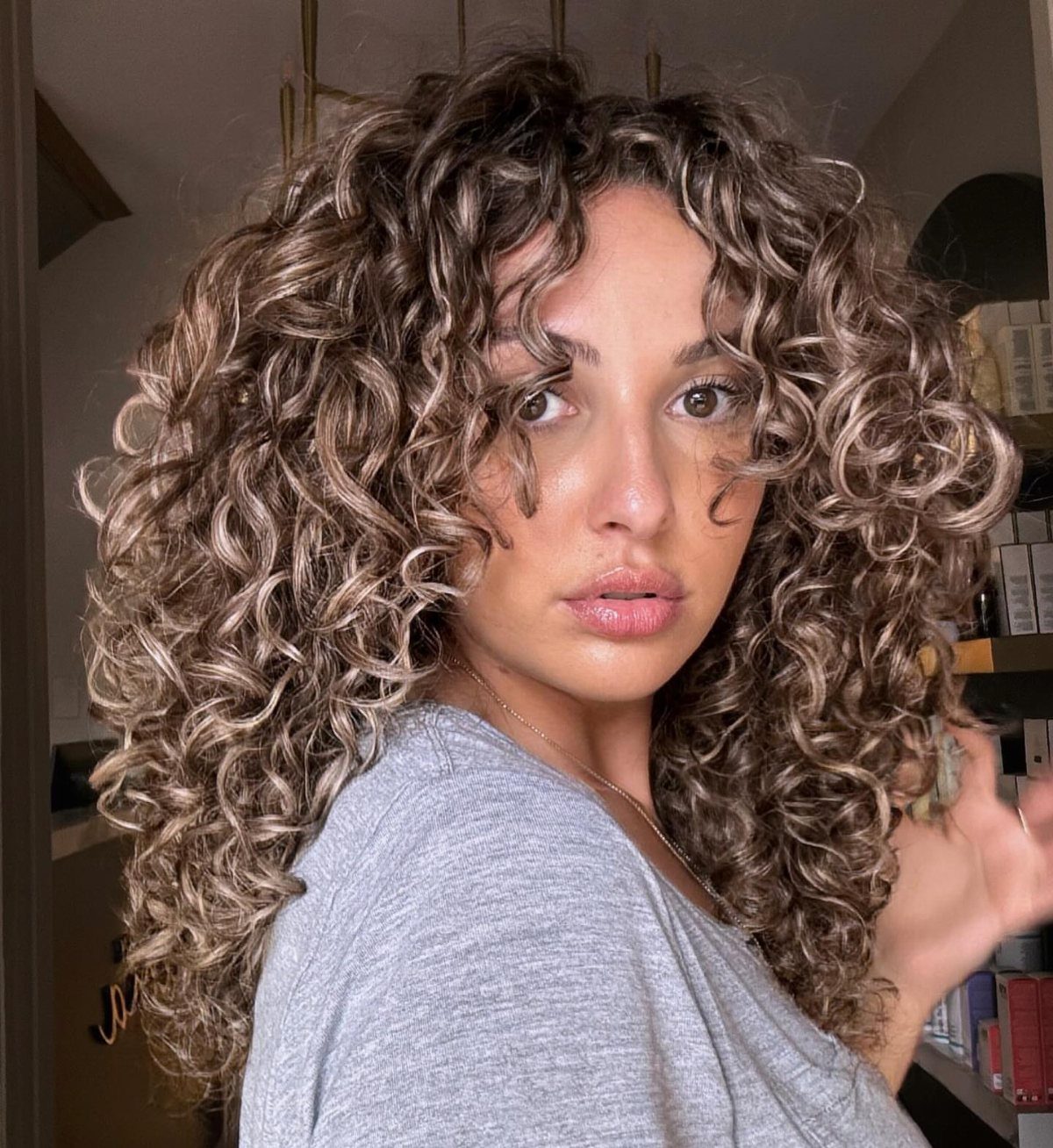 Woman with voluminous ash brown curls and subtle cool-toned highlights