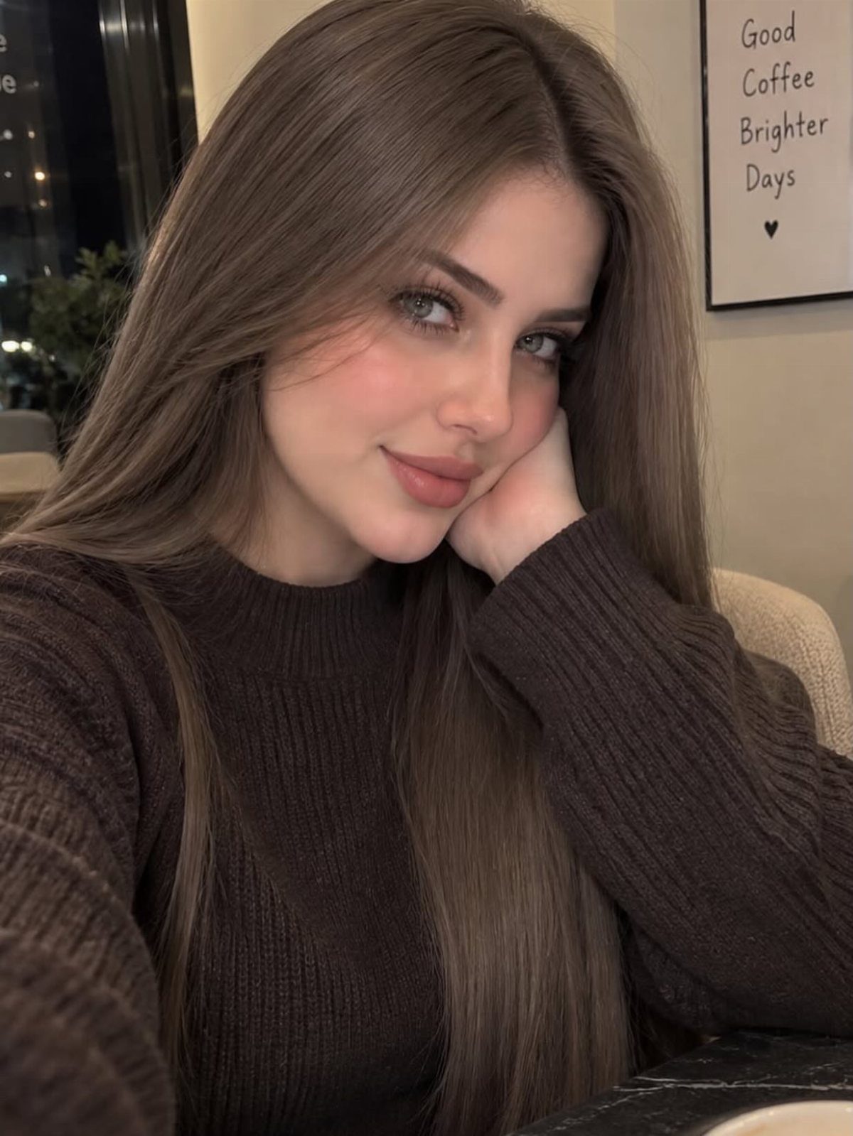 Woman with long, straight ash brown hair wearing a dark ribbed sweater