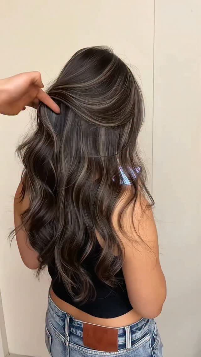 Long dark wavy hair with taupe-gray highlights, lifted to reveal layered color