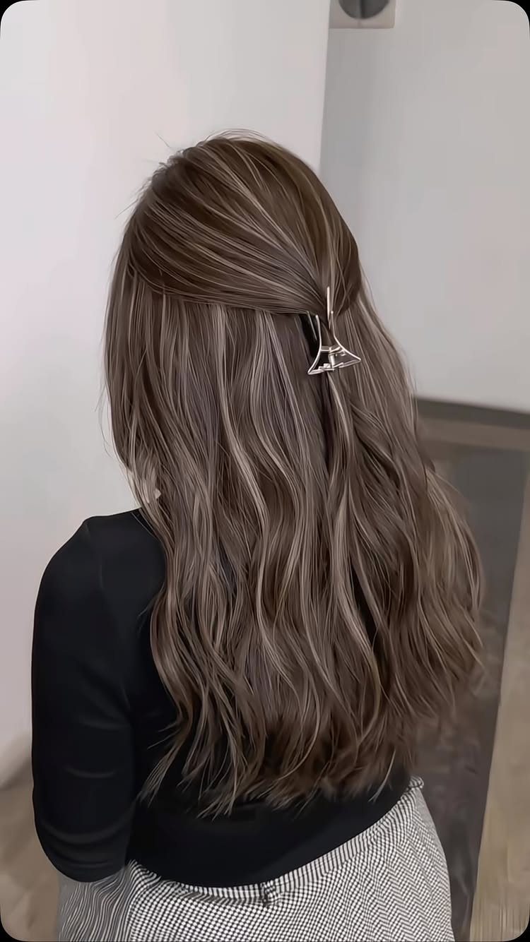 Long wavy light ash brown hair with cool gray tones and a silver clip