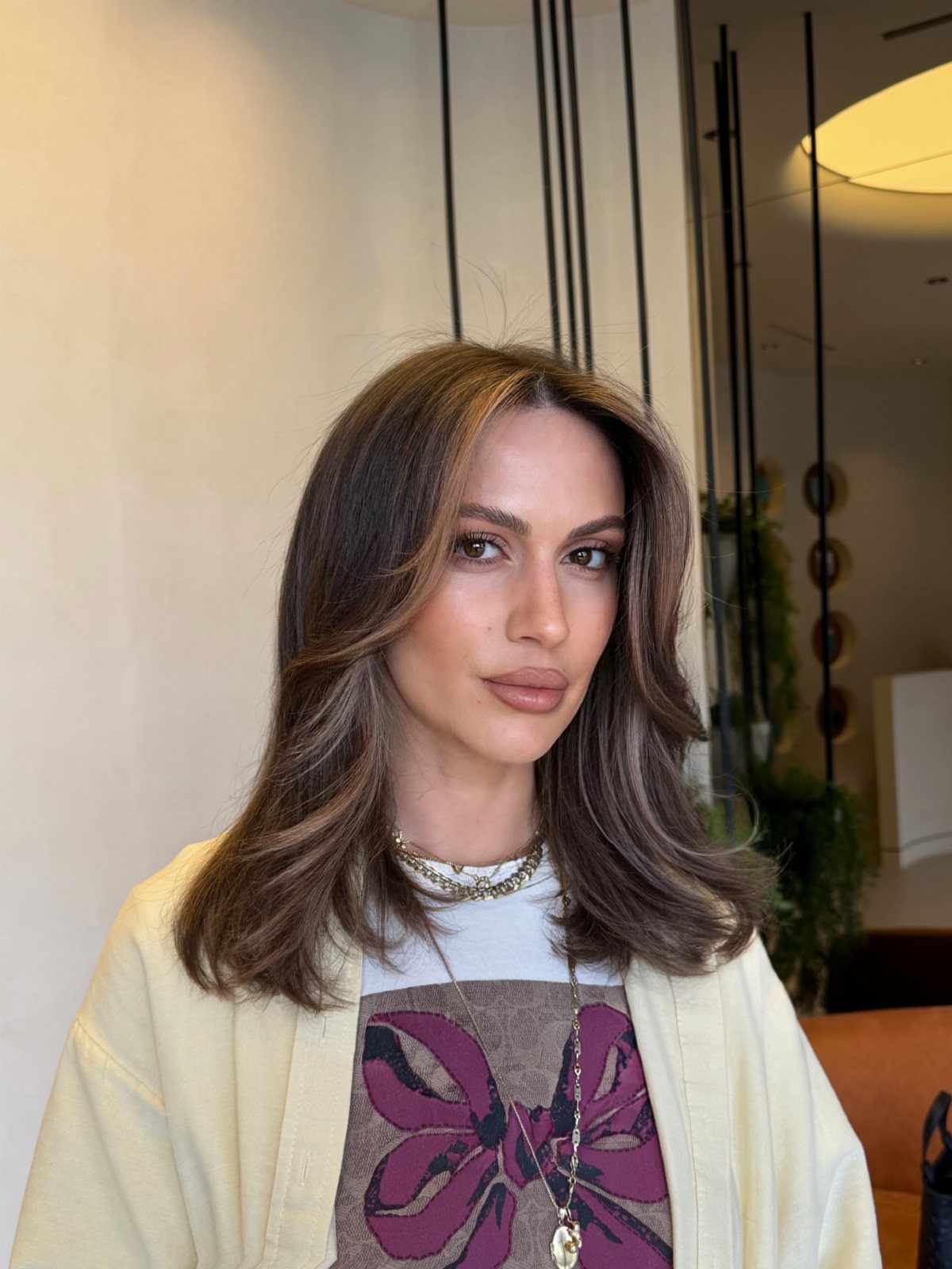 Woman with layered ash brown hair and lighter face-framing highlights