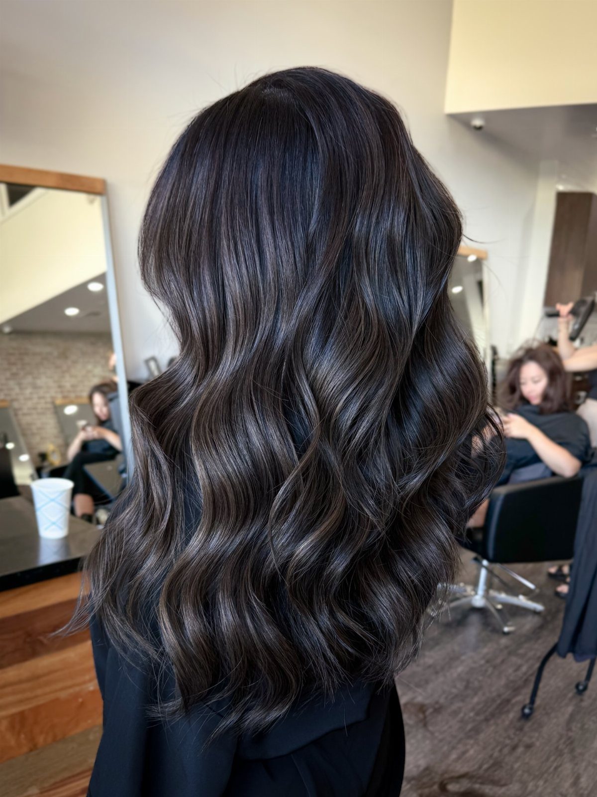 Long dark waves show subtle smoky gray-silver tones in a salon