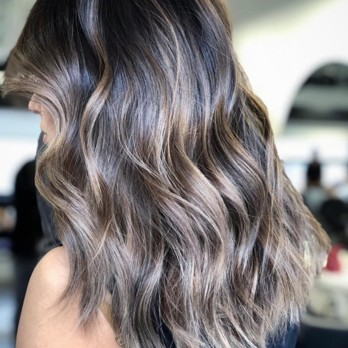 Wavy ash-brown hair with smoky dark roots and silvery highlights
