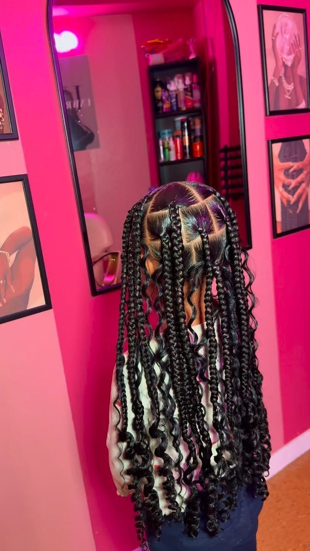Long black braids with loose curls cascade down a person’s back