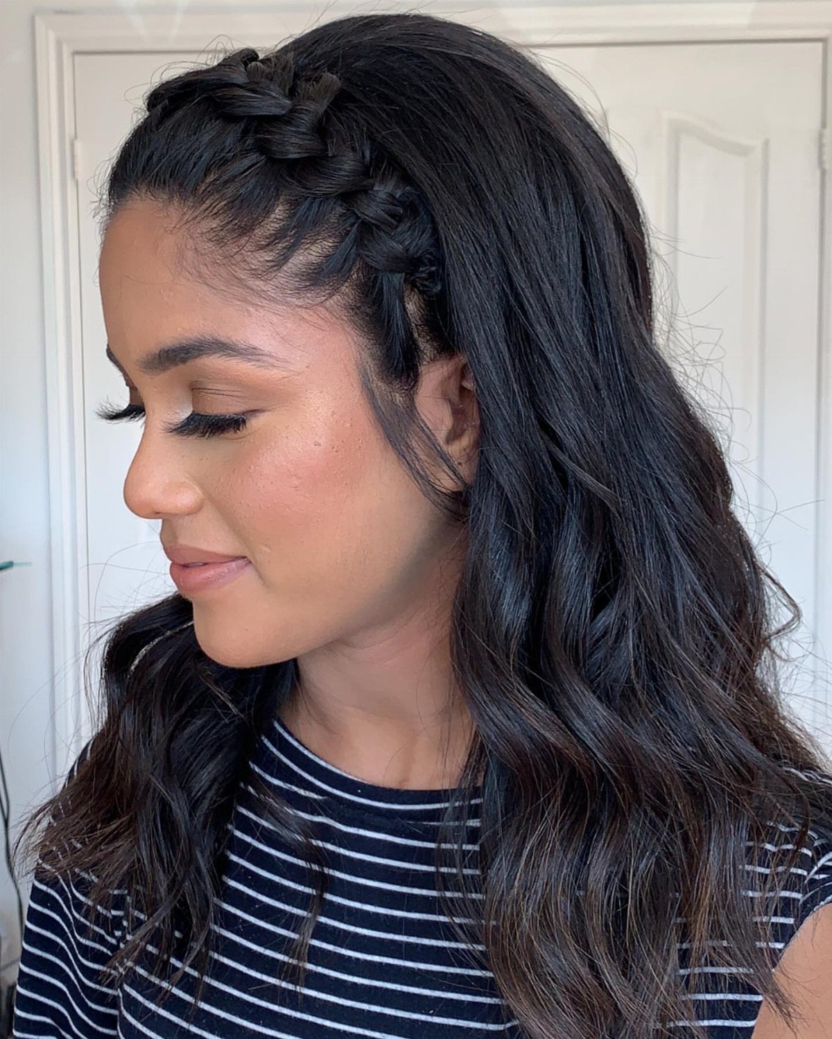 Woman with long dark waves wearing a thick braided band across her head