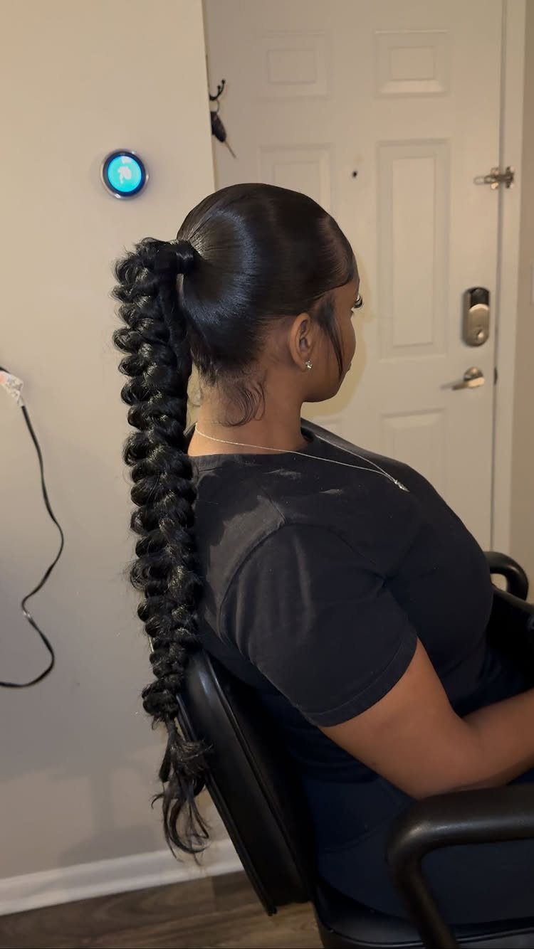 Woman with sleek black hair styled in a long braided bubble ponytail