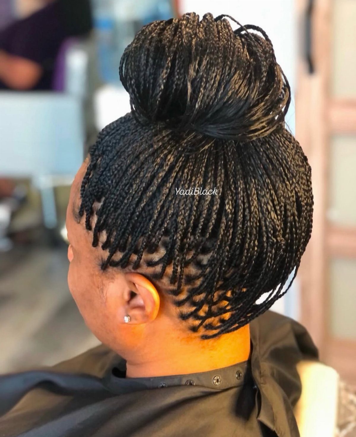 Thin black braids gathered into a large high bun on a seated person
