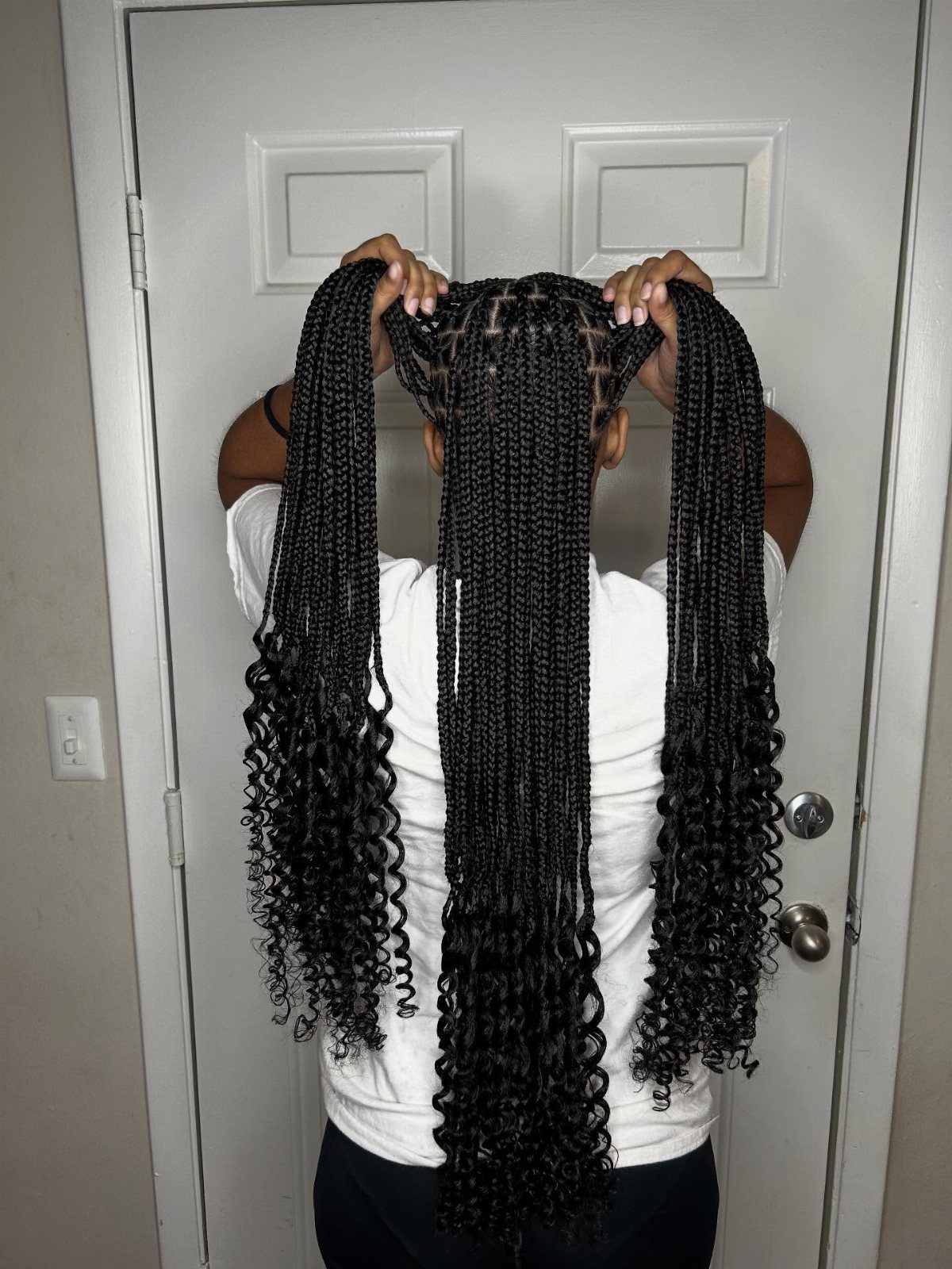 Long black braids with loose curly ends held out behind a person