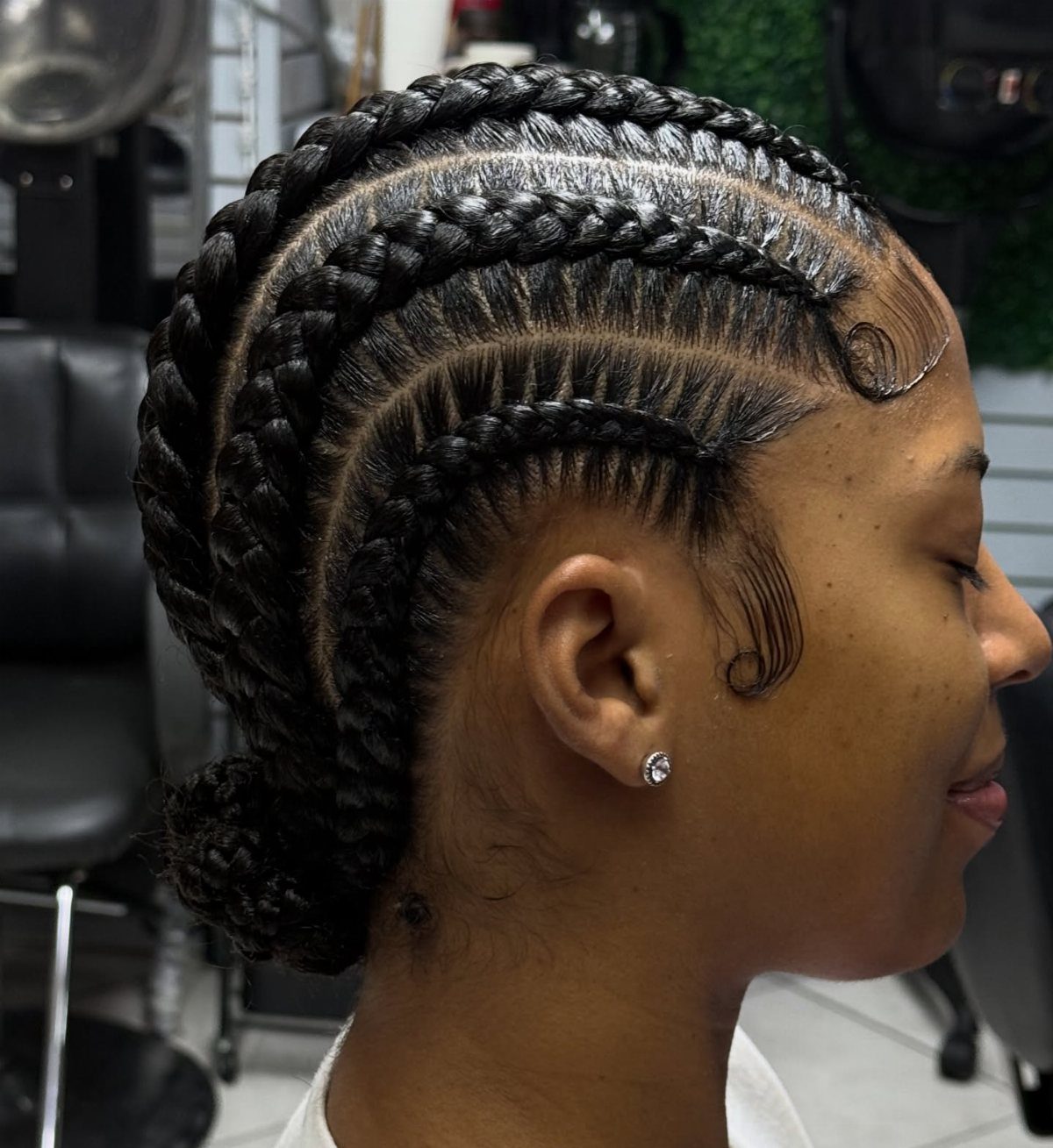 Thick black cornrows sweep closely back from the hairline in a salon
