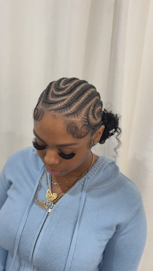 Feed-in cornrow braids curve across a woman’s scalp into a gathered back style