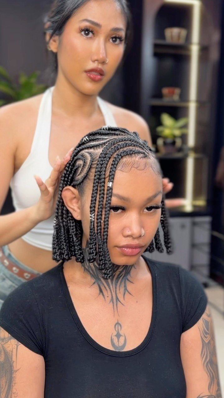 Child displaying curved scalp braids with long hanging braids in a salon