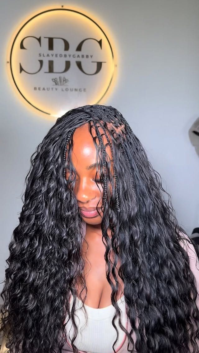 Woman showing crown braids flowing into long, loose black waves