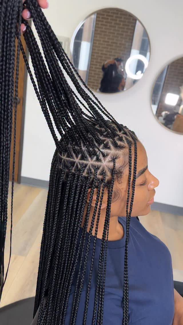 Woman with long black box braids showing triangular parts at the scalp
