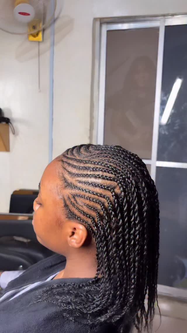 Cornrows transition into long, narrow black twists on a seated person