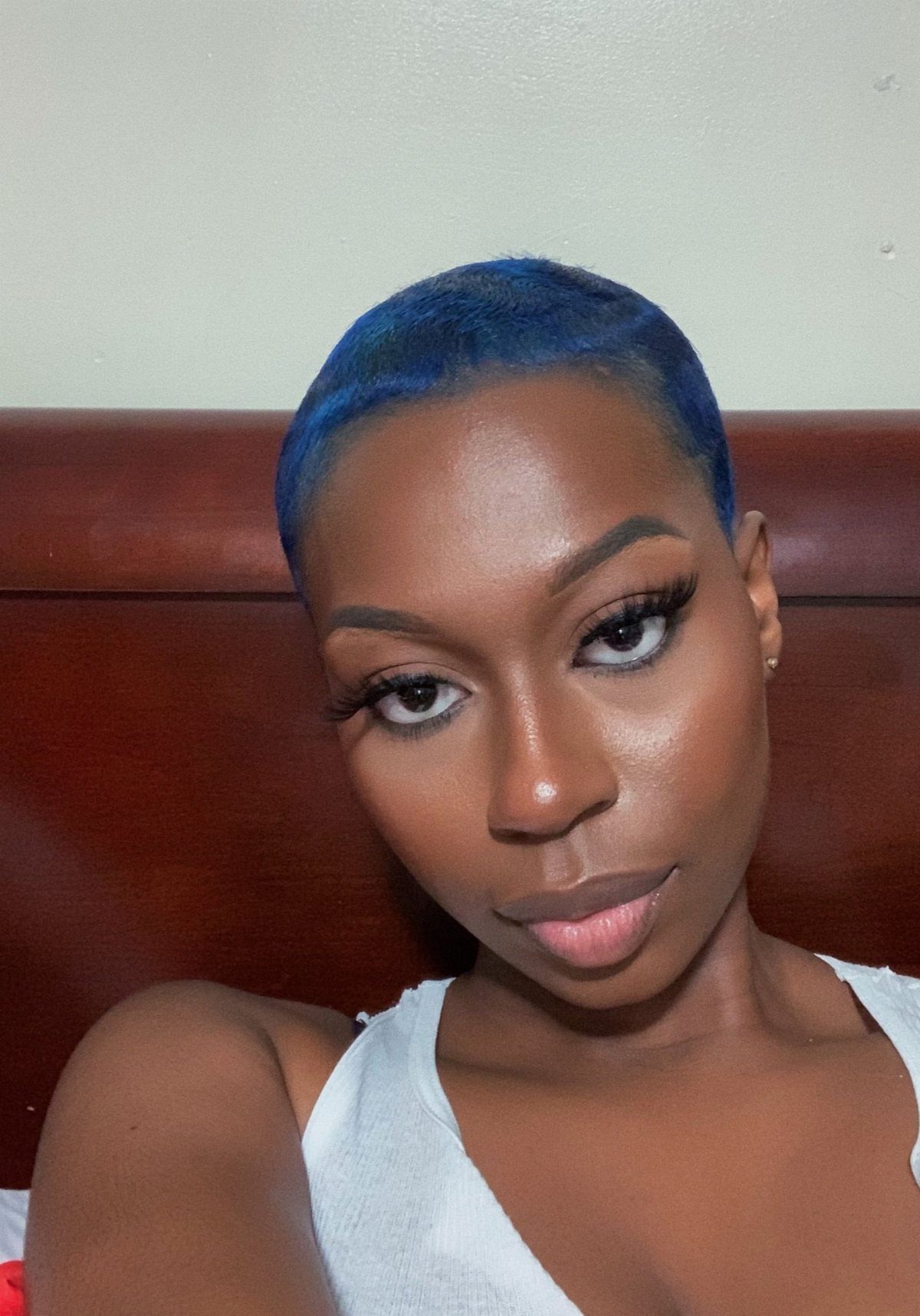 Woman with closely cropped blue-black hair taking a selfie