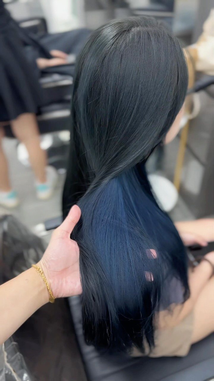 Long blue-black hair shown straight and glossy down a seated person's back