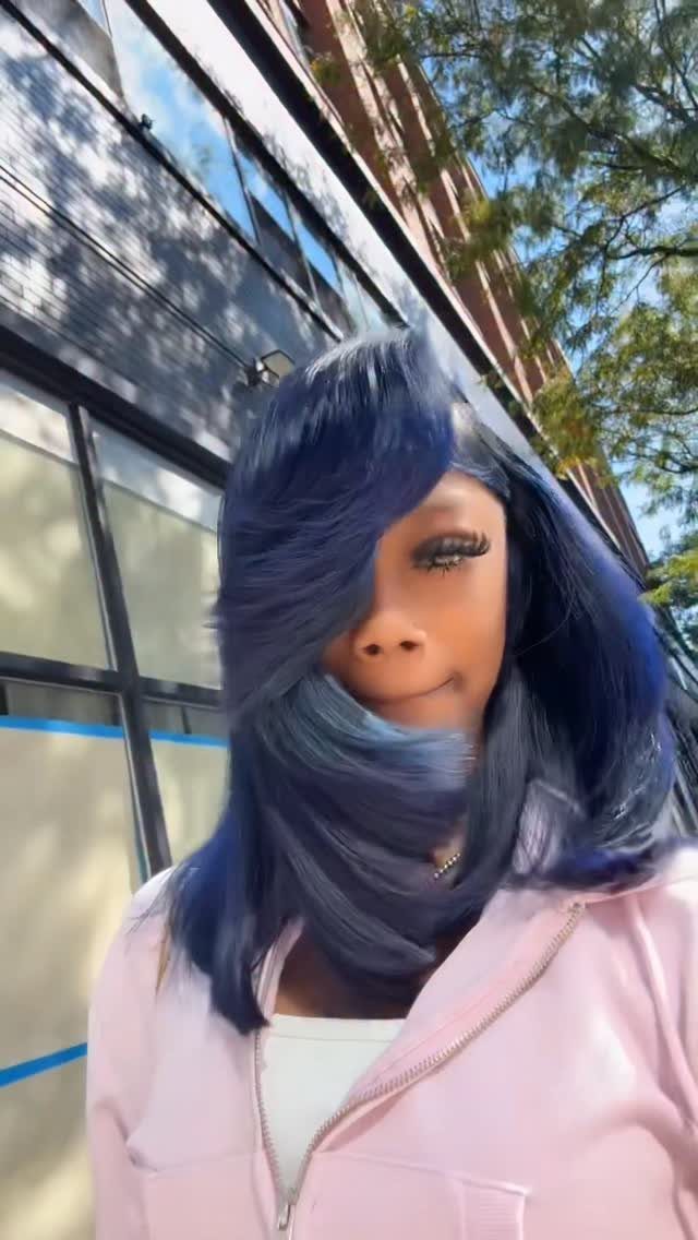 Woman with layered midnight-blue hair and side-swept bangs outdoors