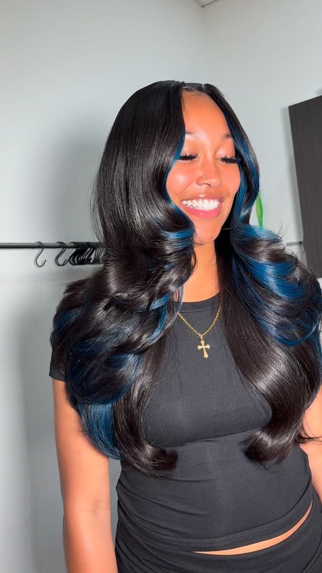 Woman with sideswept midnight hair, glossy curls, and vivid blue streaks