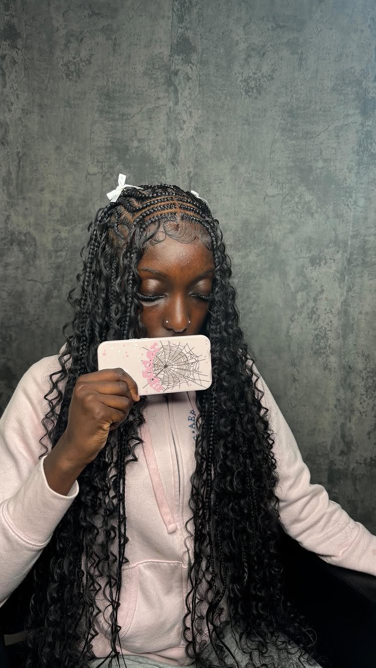 Woman with long geometric black braids and loose curls holds a pink card