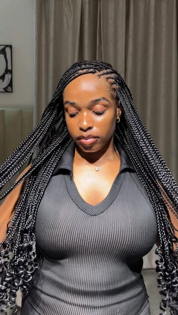 Woman posing with long black braids and curly ends over her shoulders