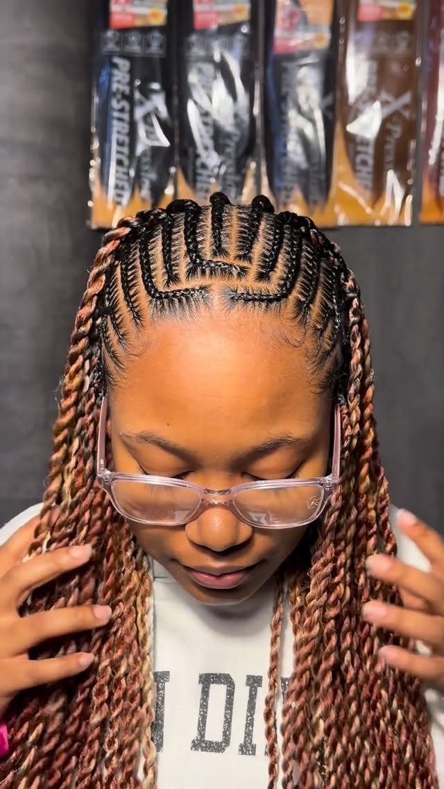 Feed-in cornrows leading into long brown and black braids on a person