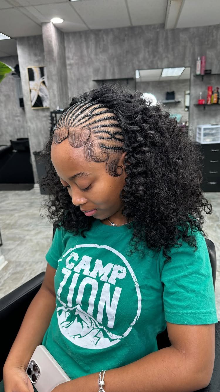 Half-up black braids transition into loose, voluminous curls around a seated woman's shoulders