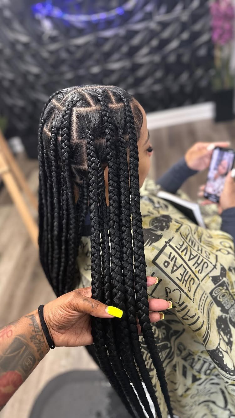 Long black knotless braids displayed from behind in a salon chair