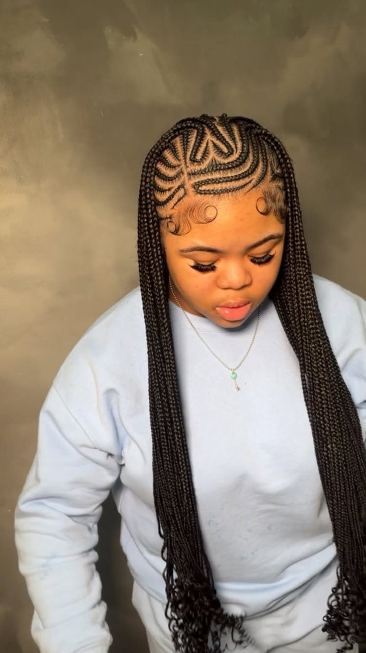 Person wearing long side-swept cornrows with patterned partings and curly ends