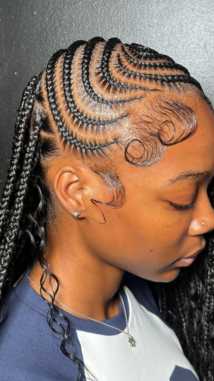 Curved scalp cornrows feed into long hanging braids beside styled baby hairs.