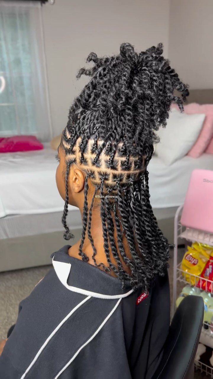 Long black two-strand twists hang from square parts beneath a high curly puff