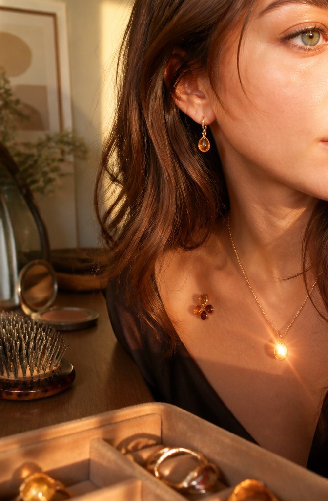 Woman wearing gold earrings rose-gold pendant amber and garnet jewelry