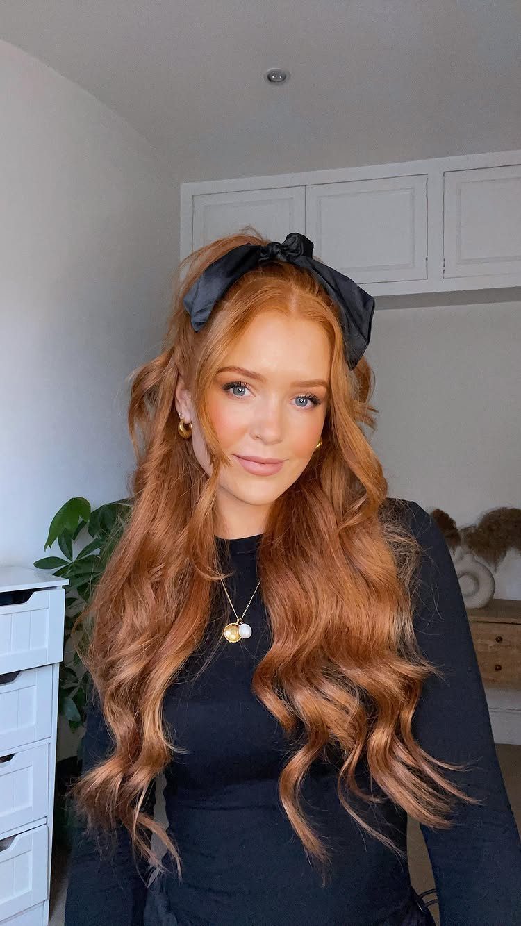 Woman with long, wavy auburn brown hair and a black headband