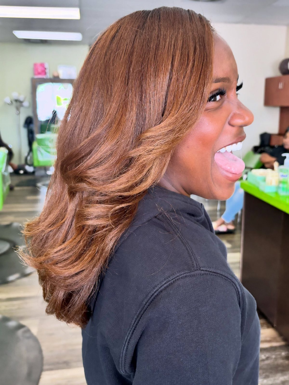 Woman showing long layered bronze-brown hair in a salon