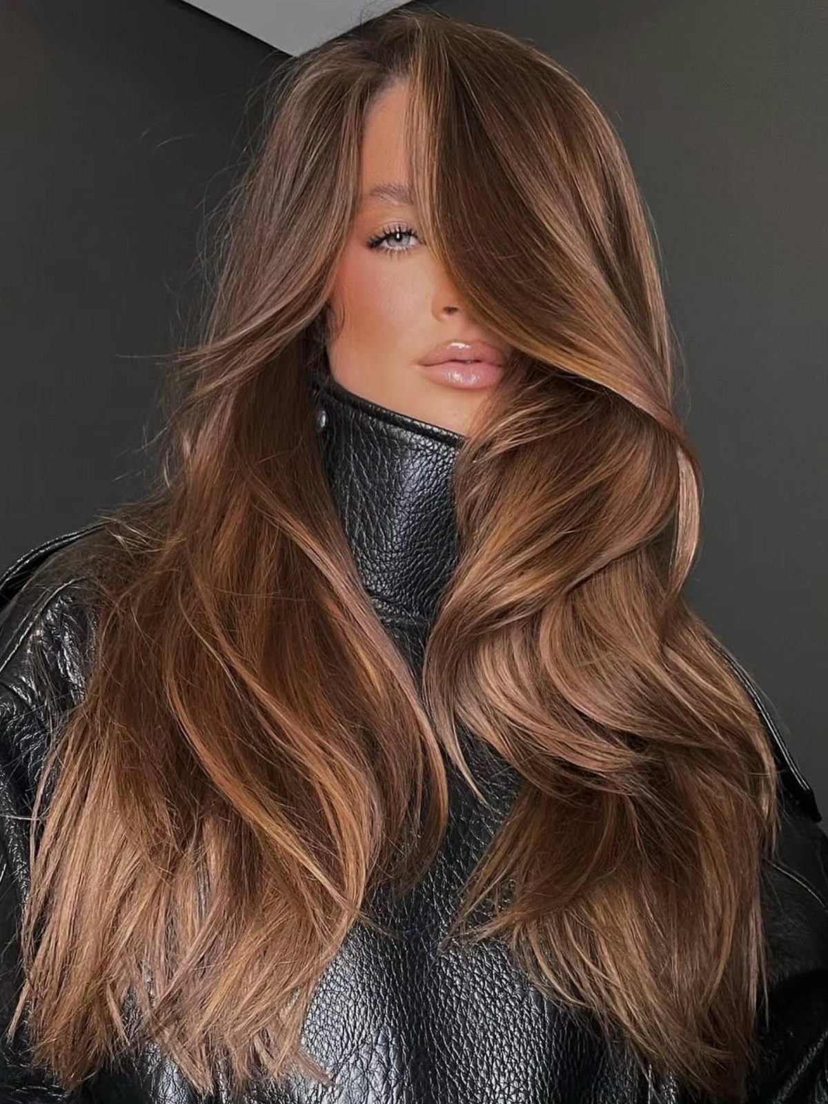 Long wavy brown hair with warm caramel highlights framing a person's face