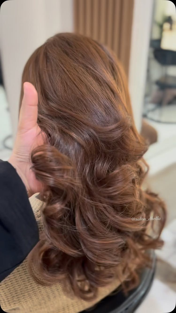 Glossy chestnut brown hair styled in loose curls and waves