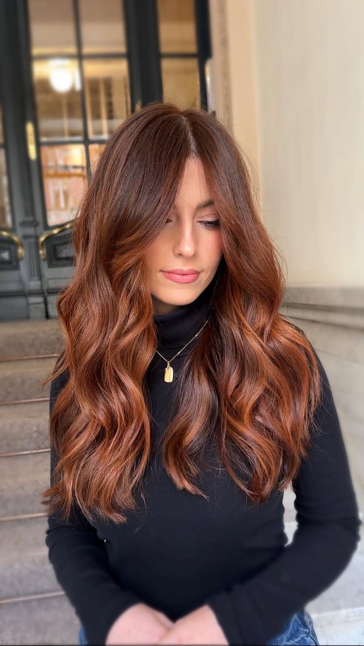 Woman showing long, wavy copper-brown hair with curtain bangs