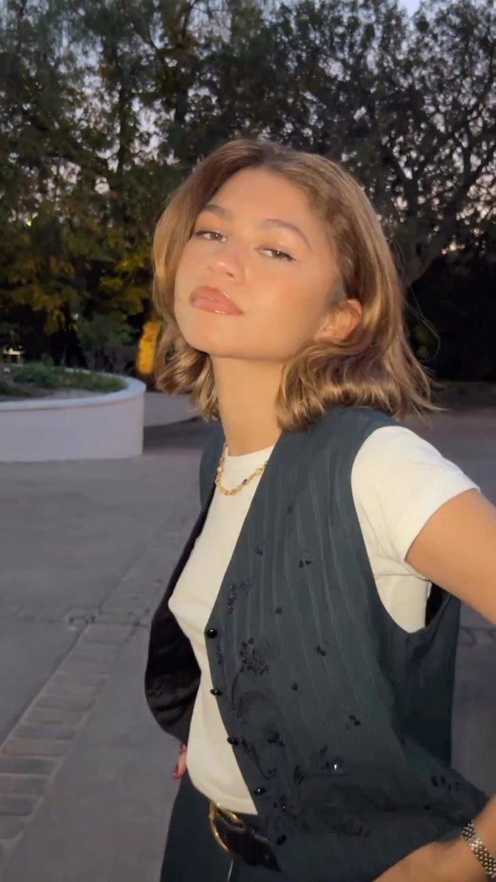 Young woman with softly highlighted light brown hair posing outdoors