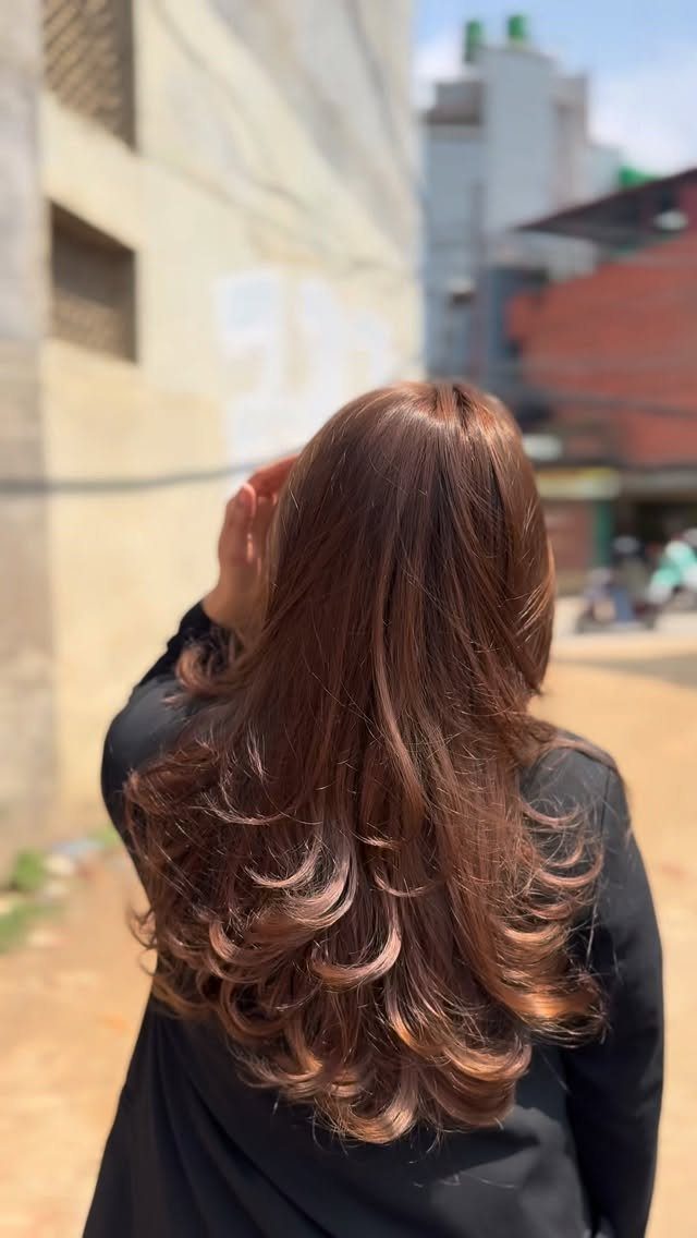 Long, rich brown layered hair with curled ends seen from behind