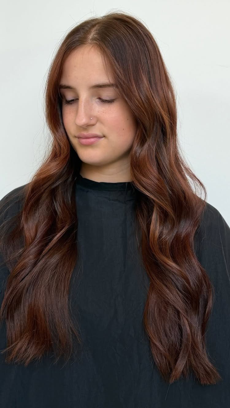 Long, wavy reddish-brown hair falls over a black top