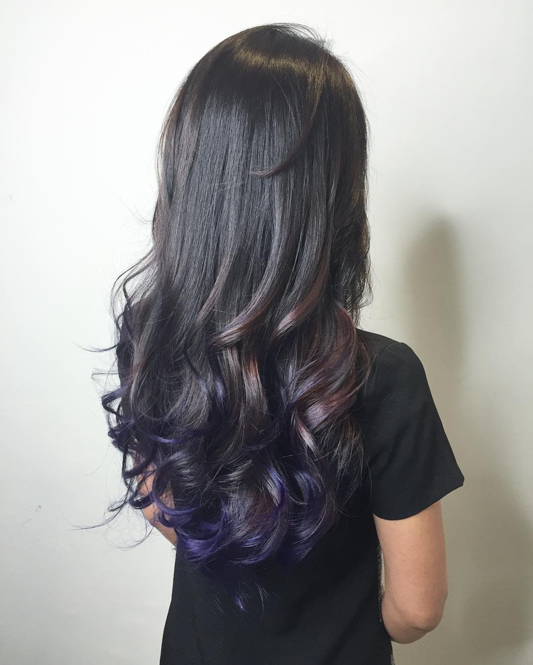 Long dark brown hair with violet-purple curled ends shown against a pale wall