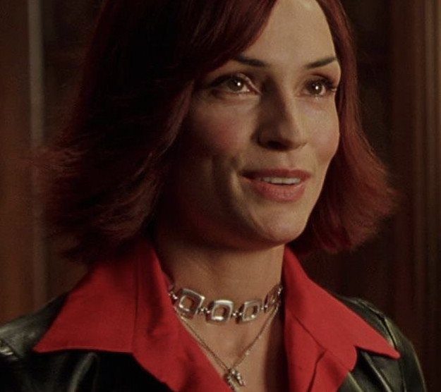Woman with auburn-red hair smiles in a red top and black leather jacket