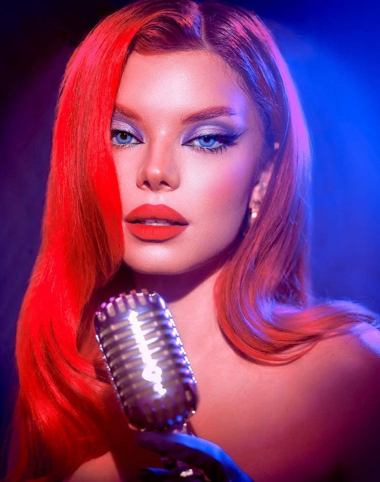 Red-haired woman with side-swept waves holding a vintage microphone
