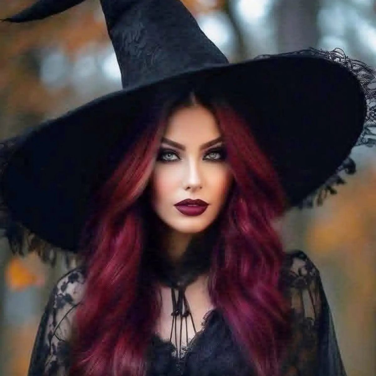 Woman with long dark red hair wearing a black pointed witch hat