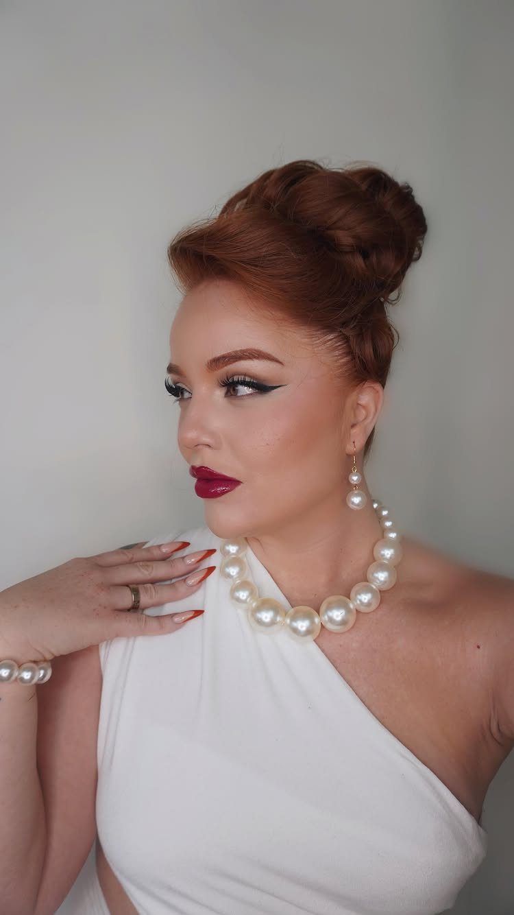 Woman with auburn hair styled in a polished sculpted high updo