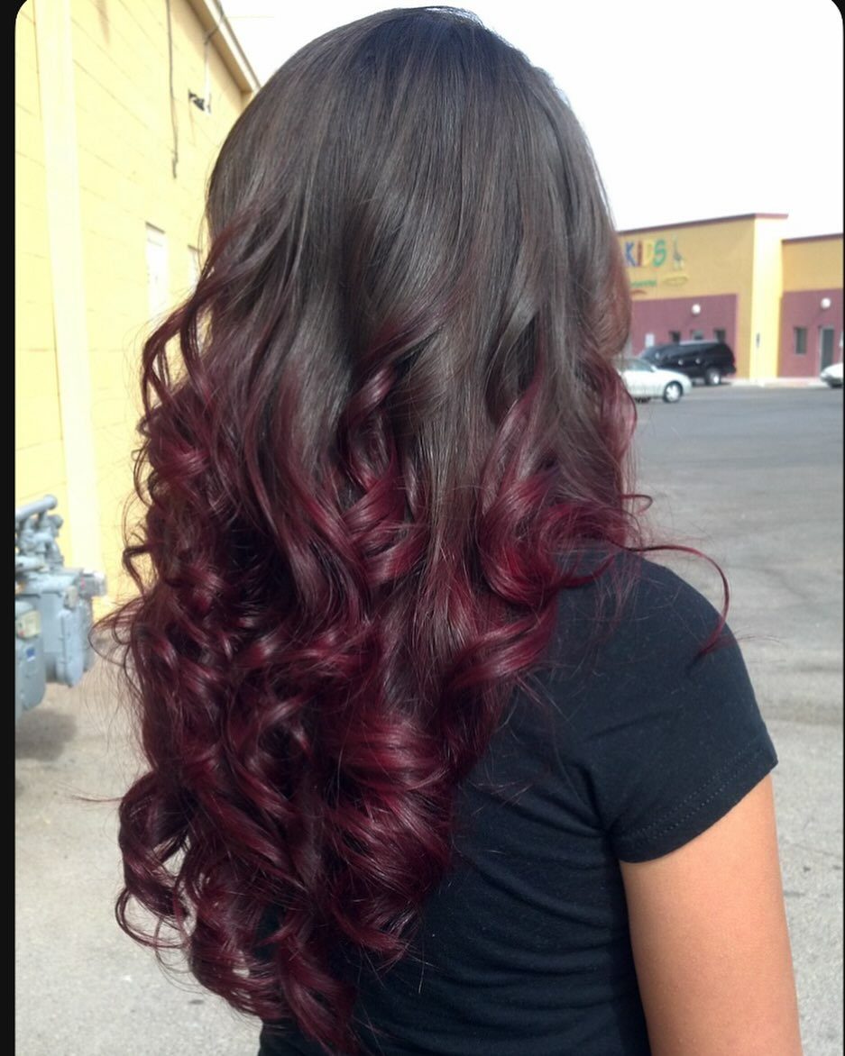 Long curled hair transitions from dark brown roots to burgundy-red ends
