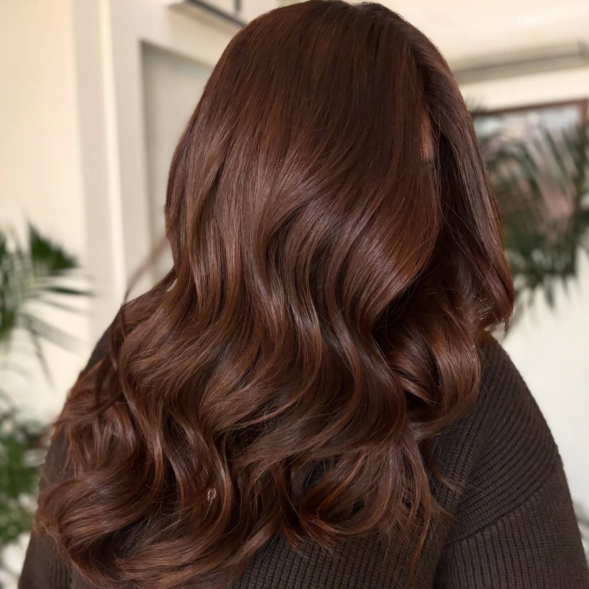Long reddish-brown waves show a glossy, subdued cherry cola hair colour