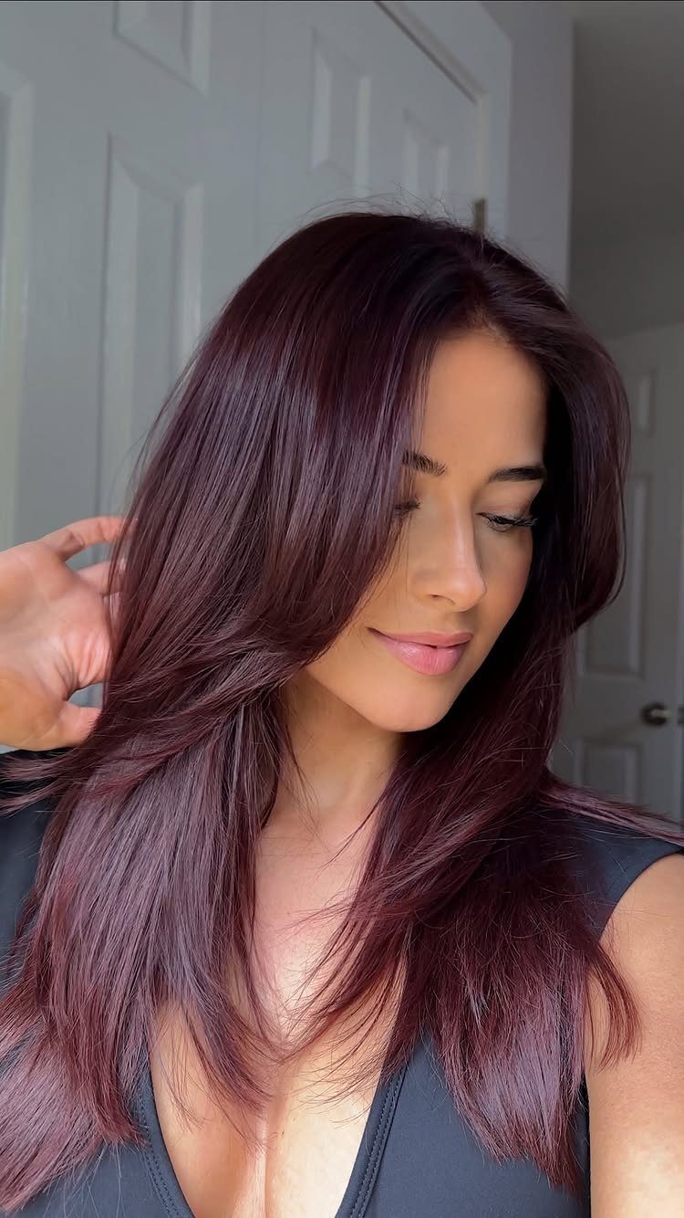 Woman displaying long medium-brown hair with a noticeable cherry-red sheen