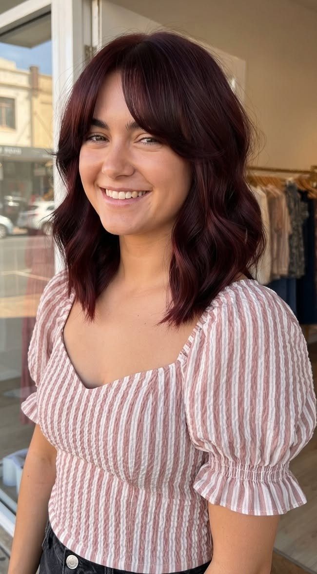 Woman with shoulder-length brunette hair tinted with cherry burgundy tones