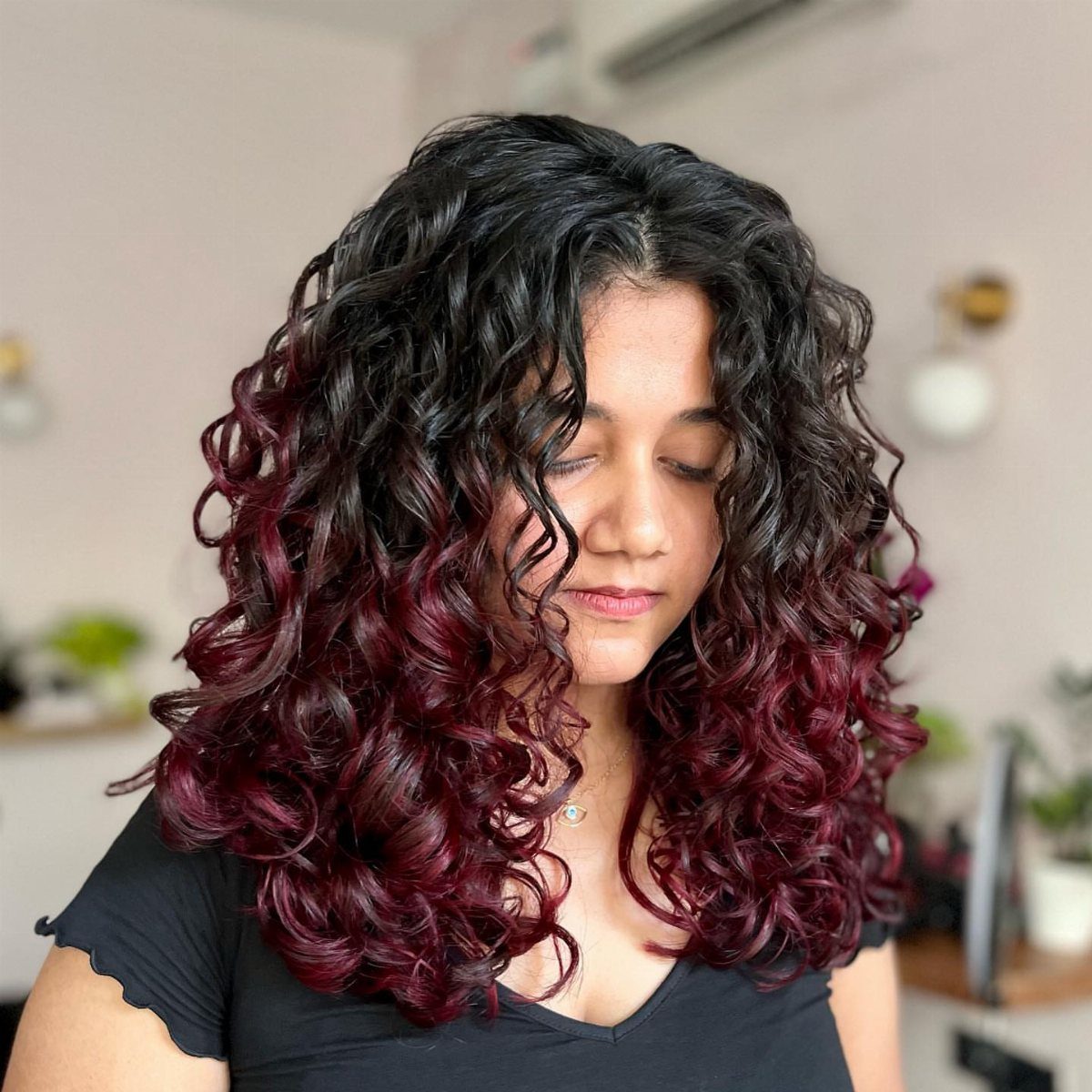 Long dark curls with deep burgundy-red color through the lower lengths
