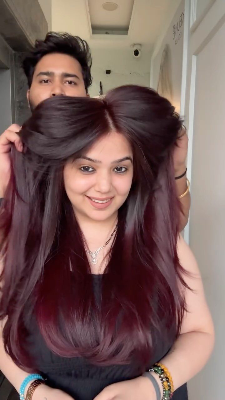 Woman displaying long, straight burgundy cherry-red hair with a center part